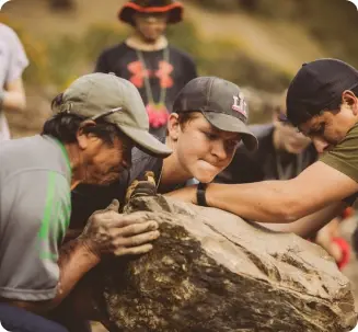 A young man on an international Service Learning trip for high school students helps locals move a large boulder 