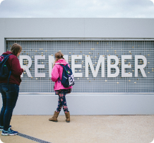Two students with backpacks in front of the words “REMEMBER” at the Utah Beach Landing Museum in Normandy on an EF D-Day tour