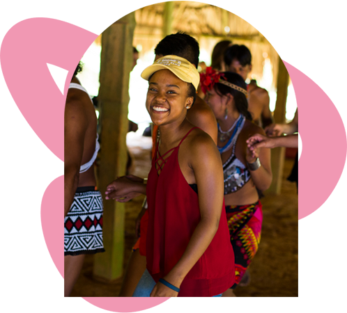  A cheerful woman in a red top and yellow hat beams at the camera, radiating happiness and confidence.