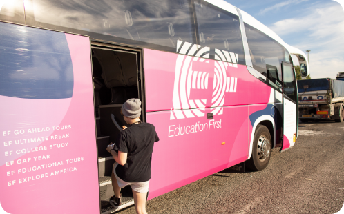 A student getting on board a pink EF tour bus