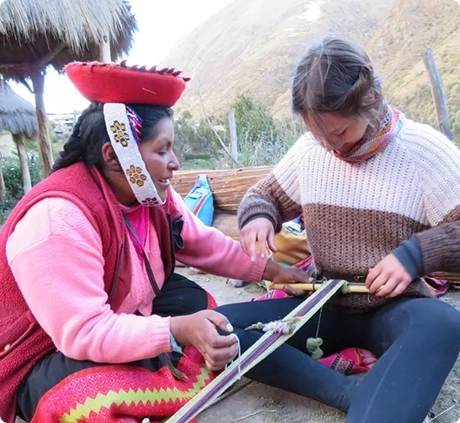 Photo of a Peruvian woman teaching student traveler Abby Peruvian weaving history and how to spin wool into yarn on one of our popular tours in Peru” with EF